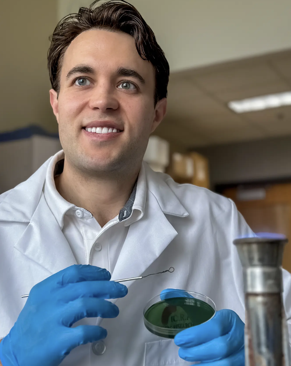 Kyle Brumfield in white lab coat holding petri dish